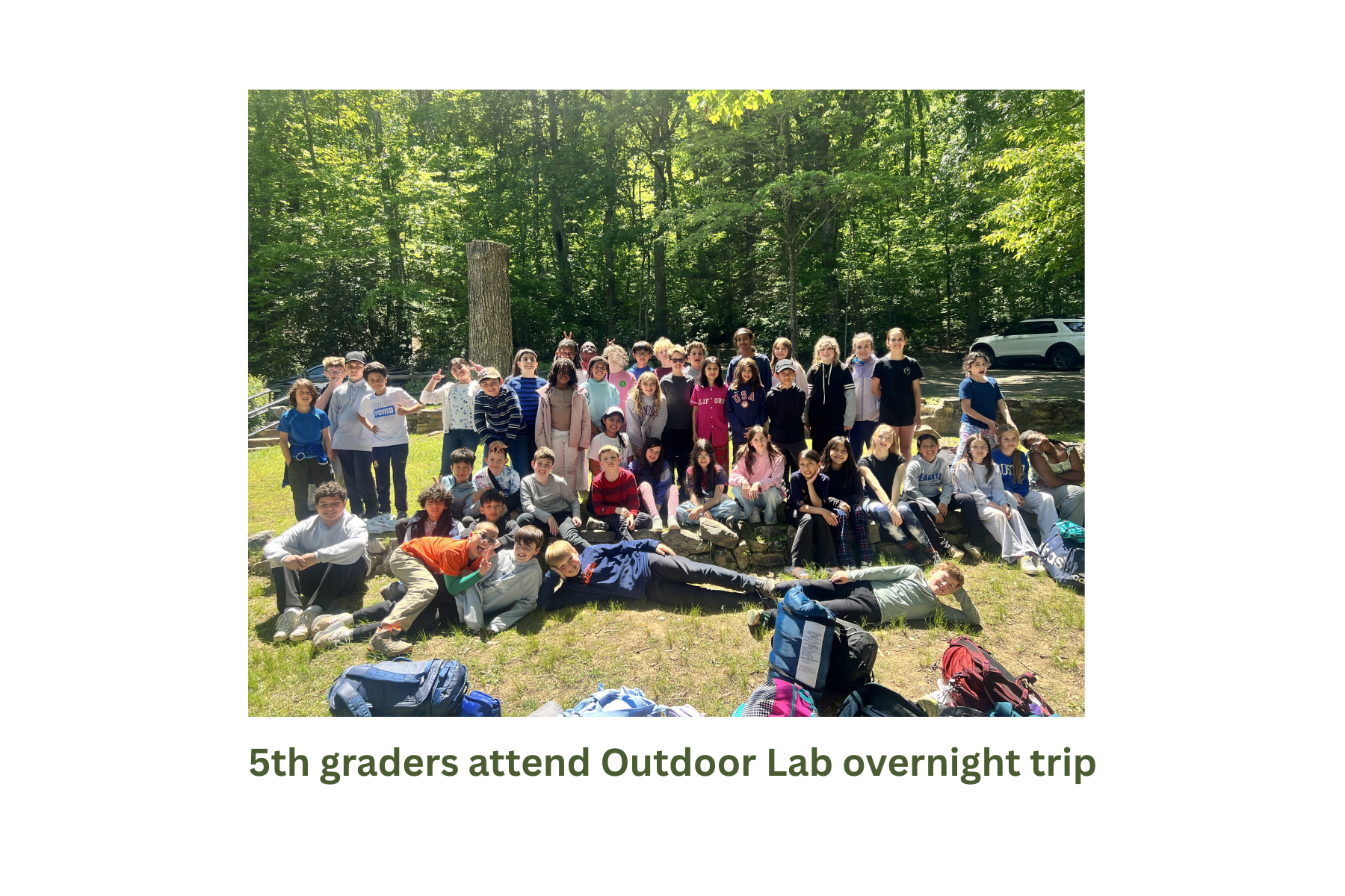 5th graders attend outdoor lab overnight trip with a group picture in front of trees